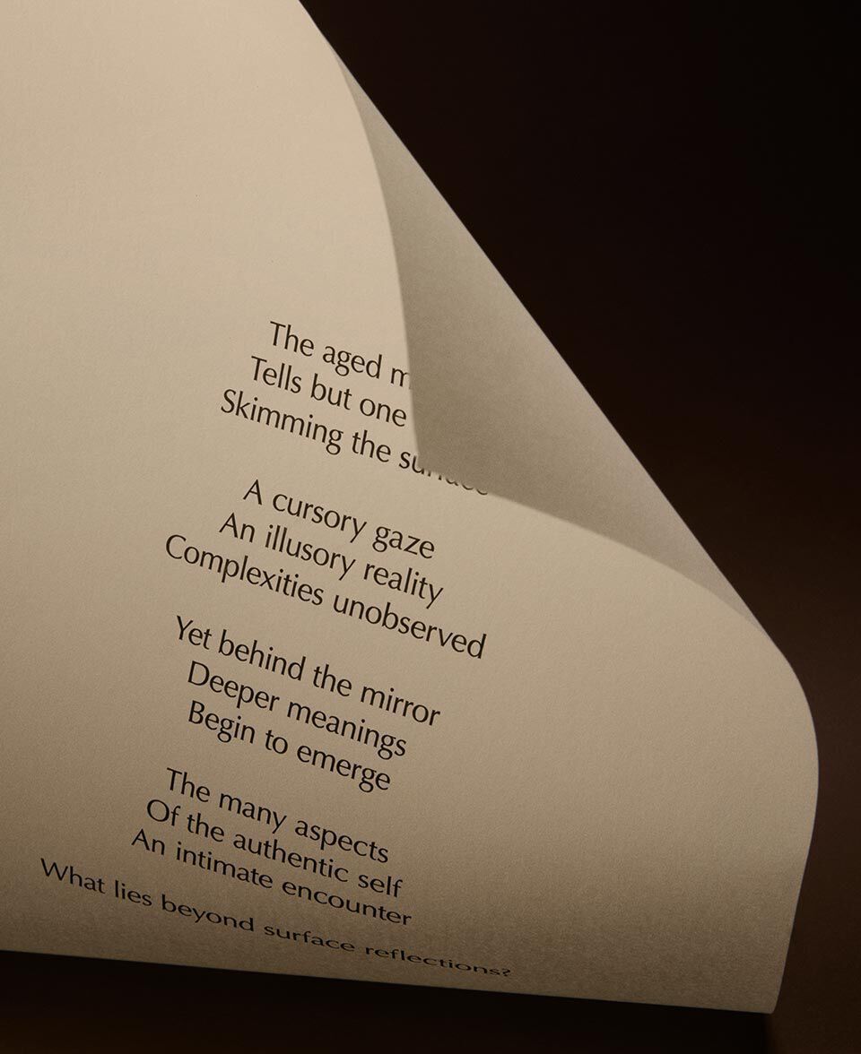 Carta color crema piegata, con versi poetici stampati, in un'essenziale ambientazione scura.
