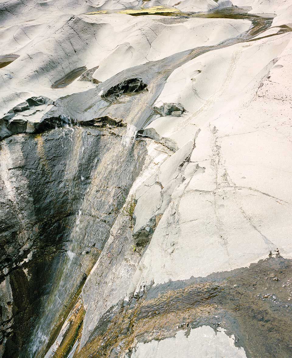 Pallida parete rocciosa erosa dal tempo, con fluidi motivi minerali e striature.