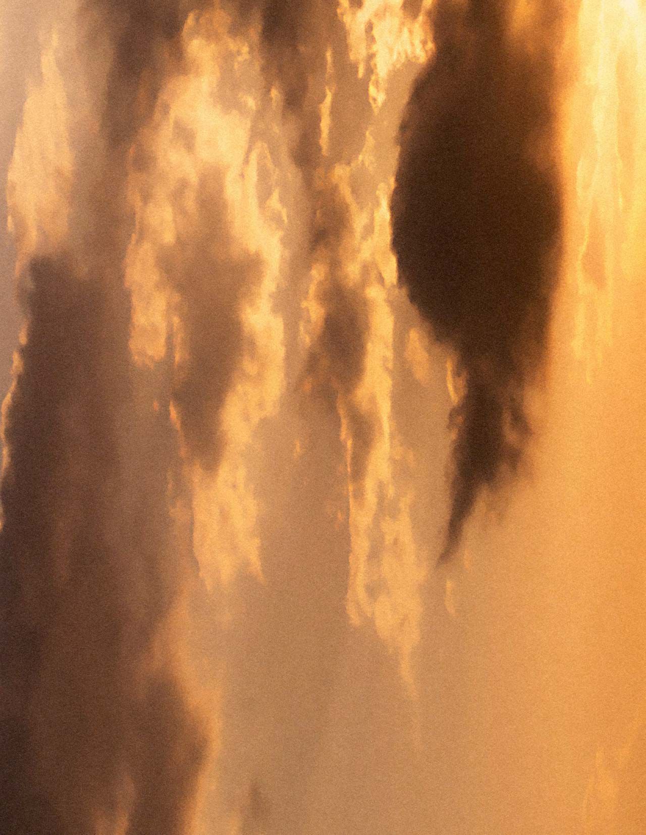 Cielo al tramonto dorato, con nuvole stratificate in calde tonalita ambrate, luce morbida e diffusa, e formazioni nuvolose piu scure che attraversano la scena.