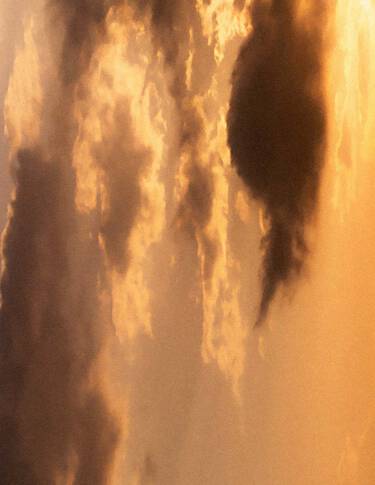 Cielo al tramonto dorato, con nuvole stratificate in calde tonalita ambrate, luce morbida e diffusa, e formazioni nuvolose piu scure che attraversano la scena.