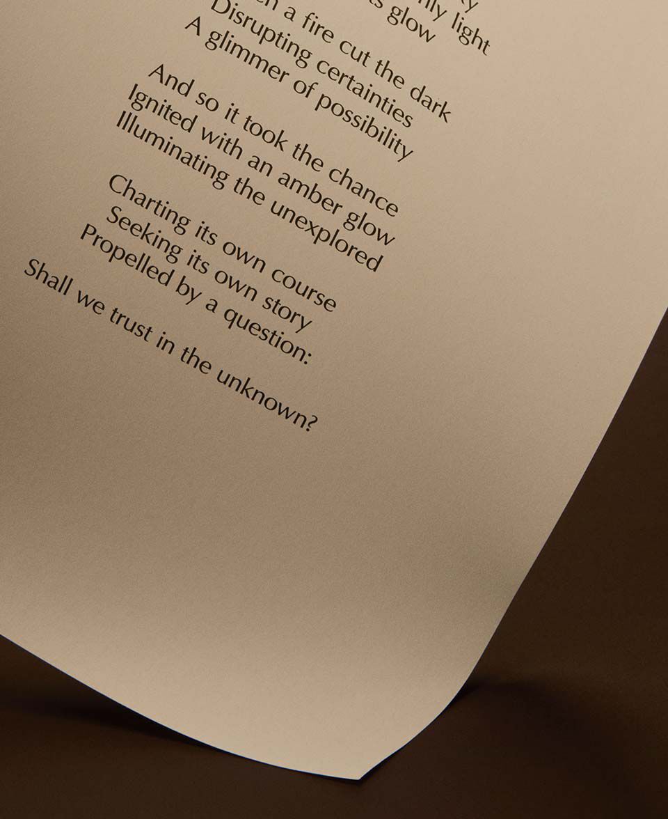 Pagina incurvata con testo poetico stampato su uno sfondo marrone scuro e caldo.