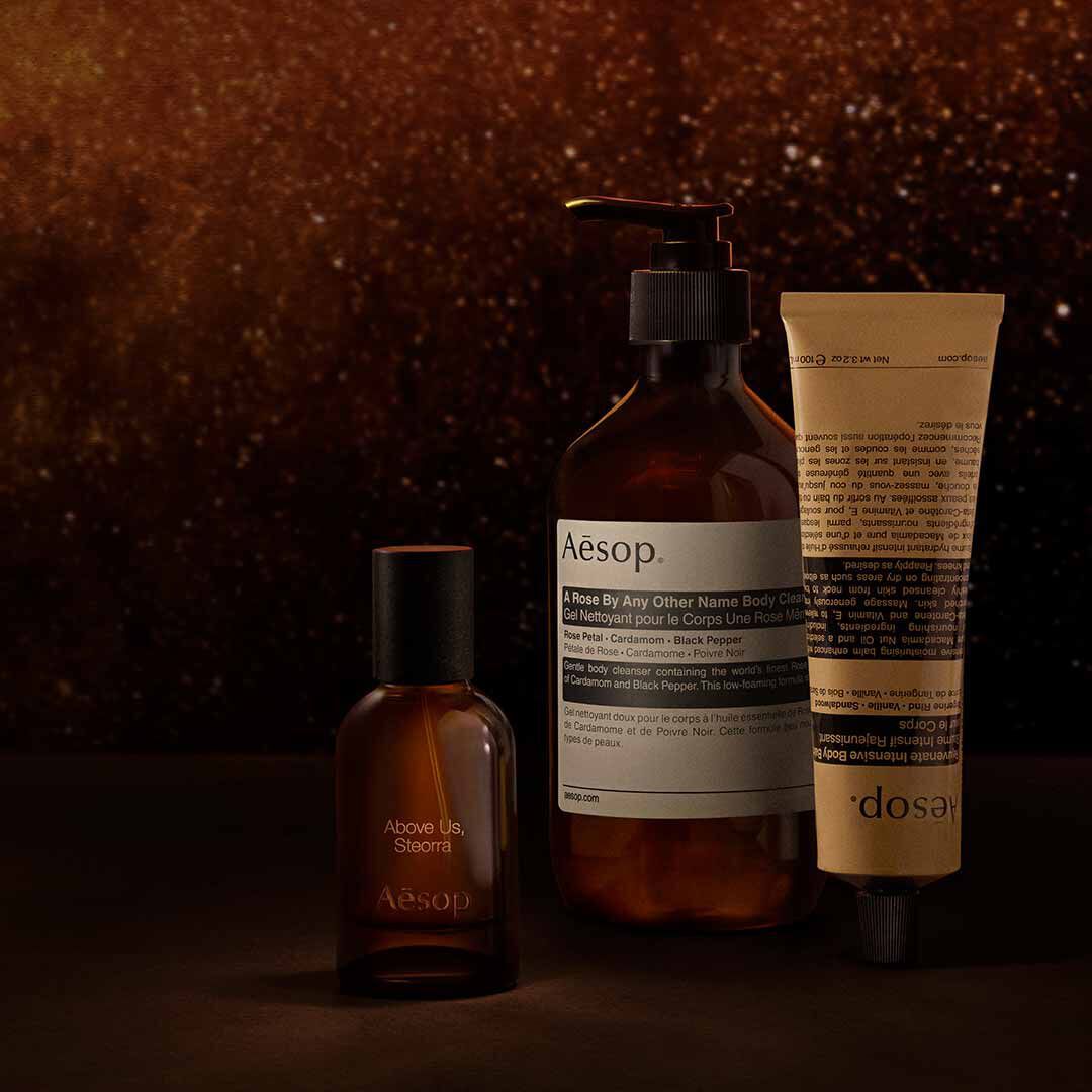 Flacone Aesop Above Us, Steorra con dispenser e tubo su uno sfondo marrone caldo e screziato.