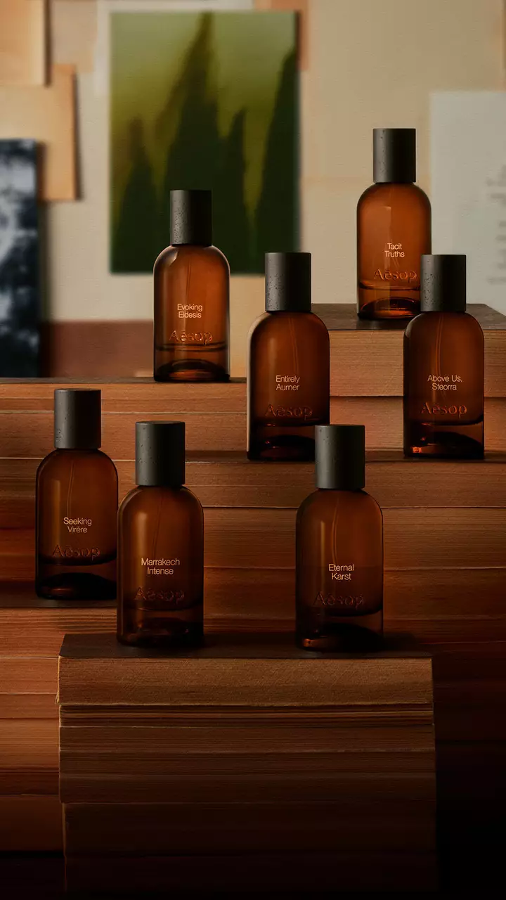 Flaconi di profumo in vetro ambrato Aesop esposti su libri impilati.