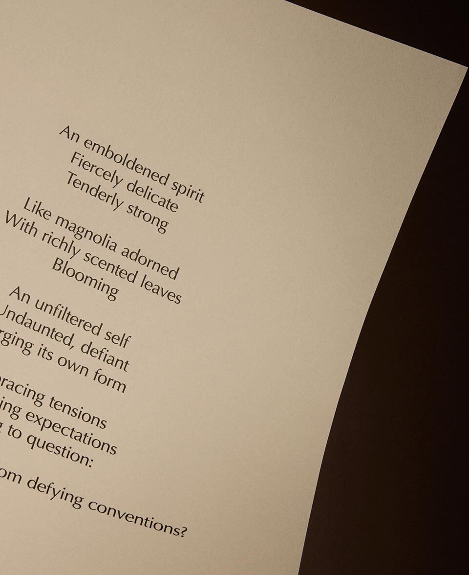 Testo poetico su una pagina color crema, delicatamente illuminata, su sfondo scuro.