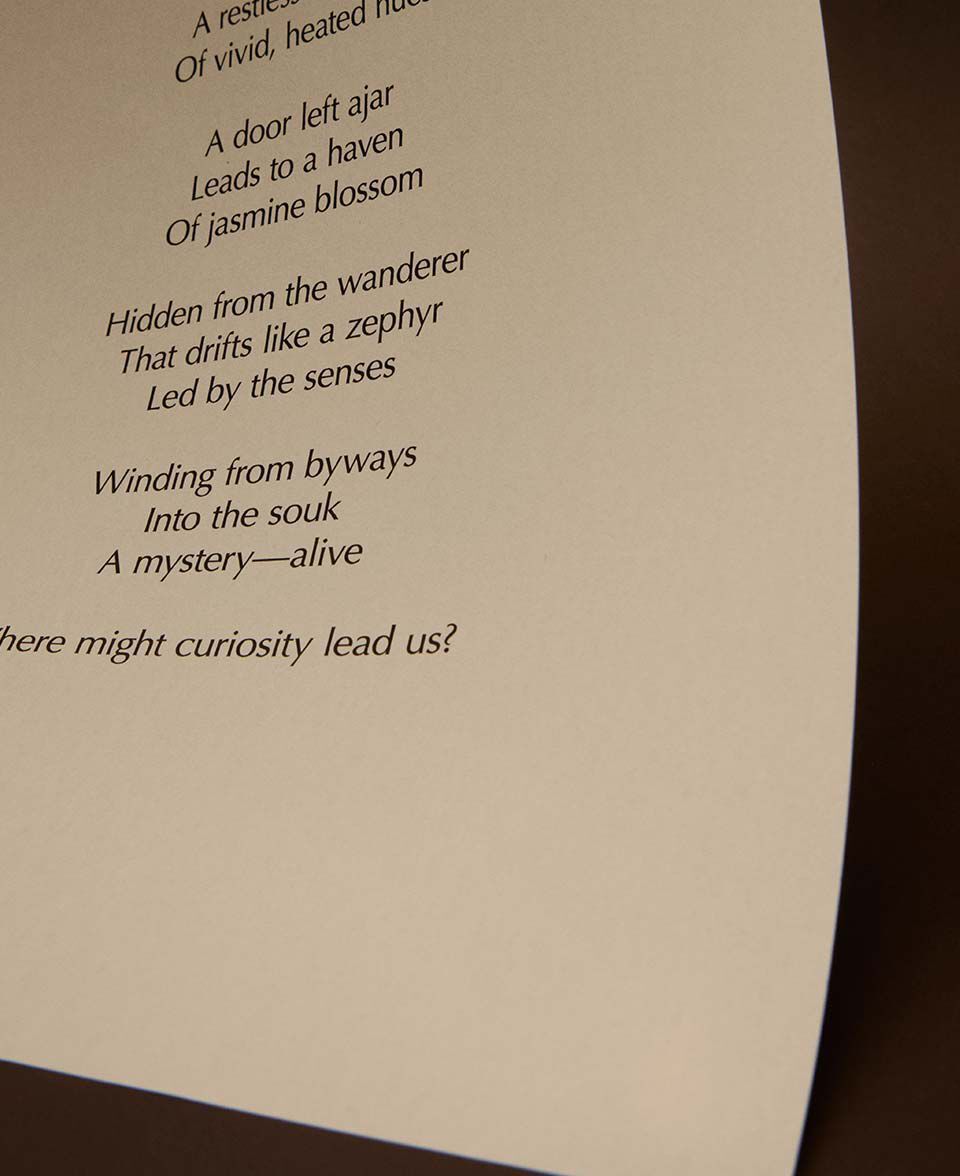 Primo piano di versi poetici stampati su un foglio di carta color crema ricurvo.