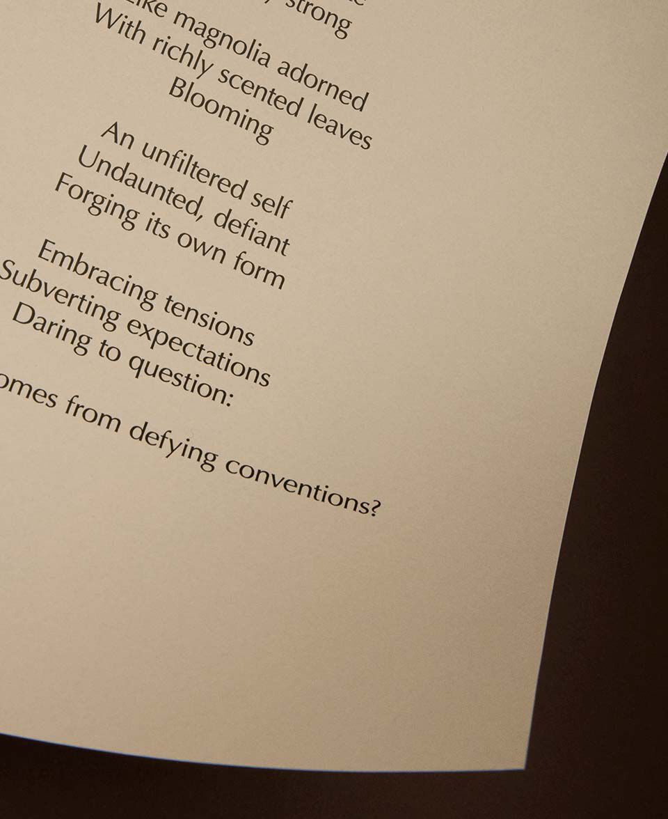 Vista parziale di una poesia stampata su carta color crema, con il bordo della pagina curvo.